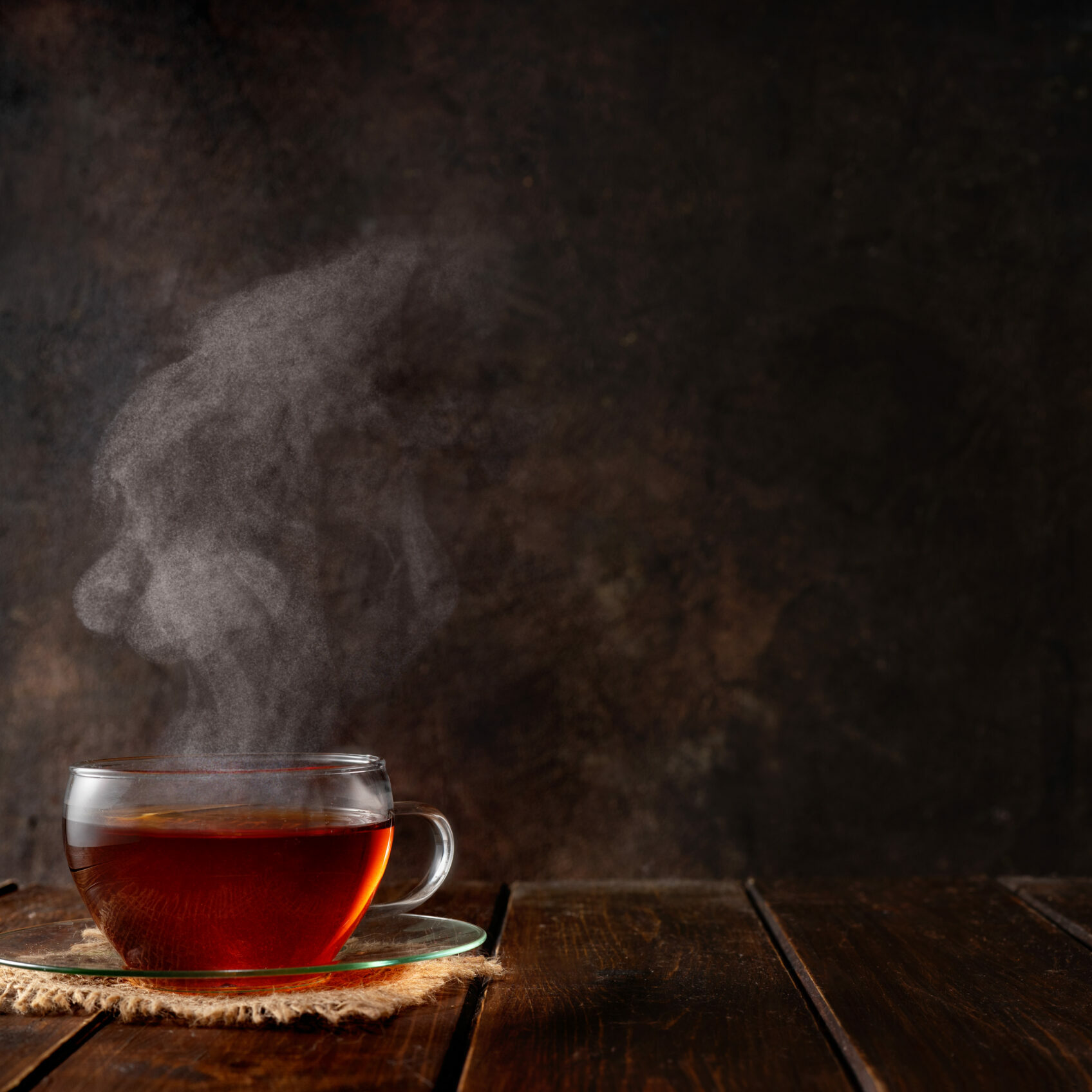 Cup of hot tea with a steam on dark rustic background. Copy space